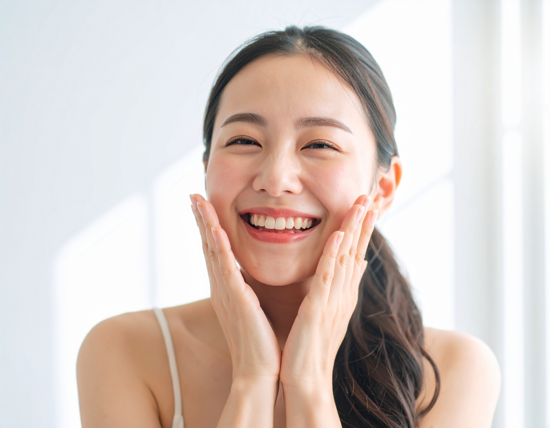 笑顔で頬に手を当てる女性の写真